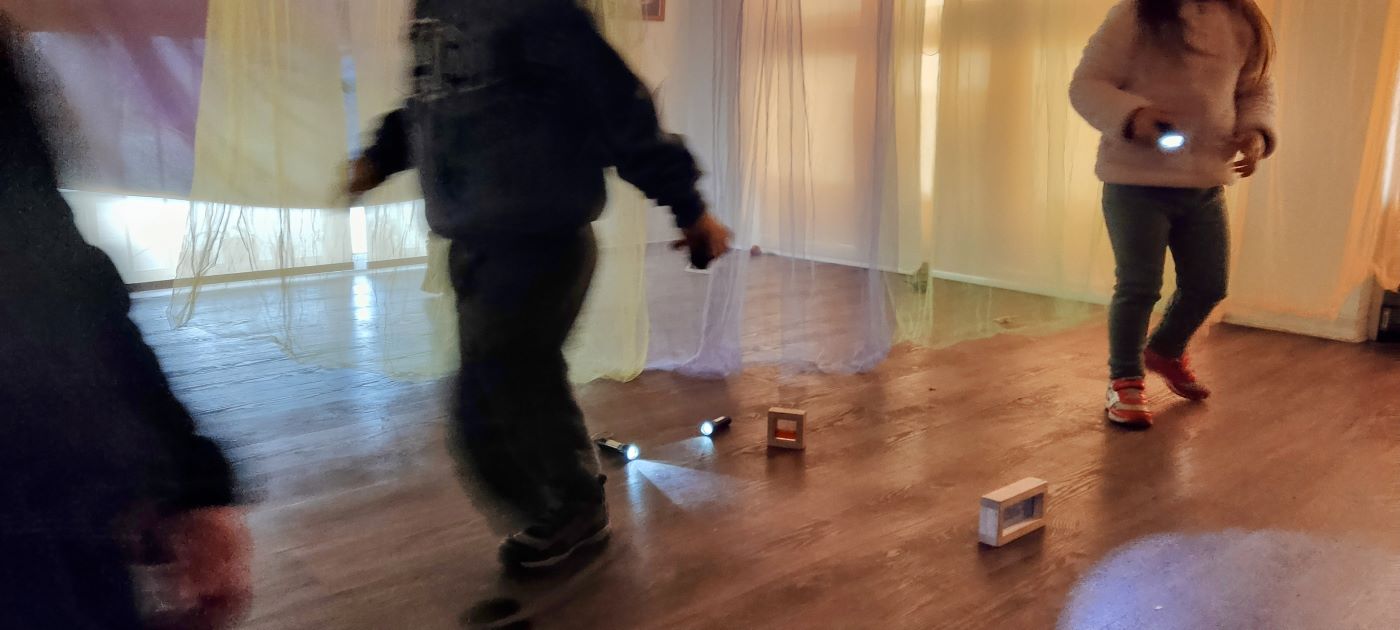 niños y niñas caminando en una sala con telas colgando