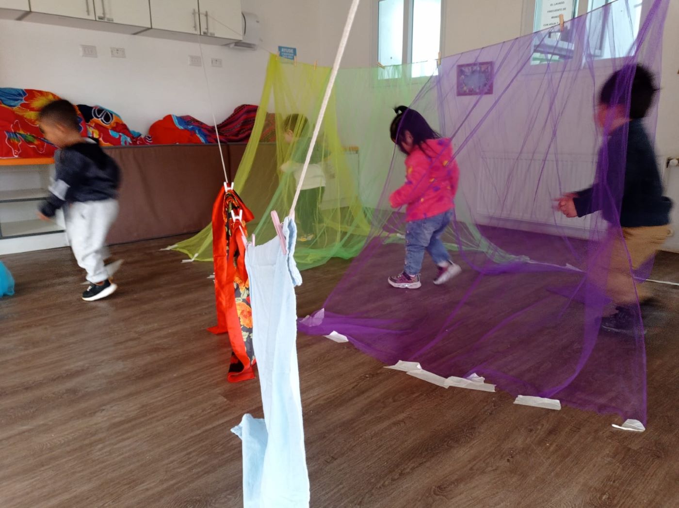 niños y niñas atravesando telas de colores
