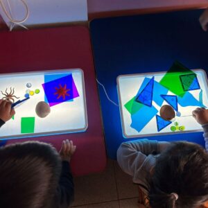 niños y niñas observando láminas transparentes sobre mesa de luz