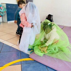 niños y niñas cubriendose con telas de colores