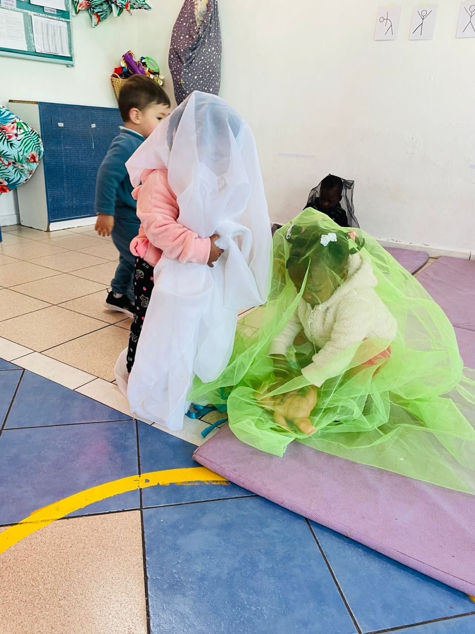 niños y niñas cubriendose con telas de colores