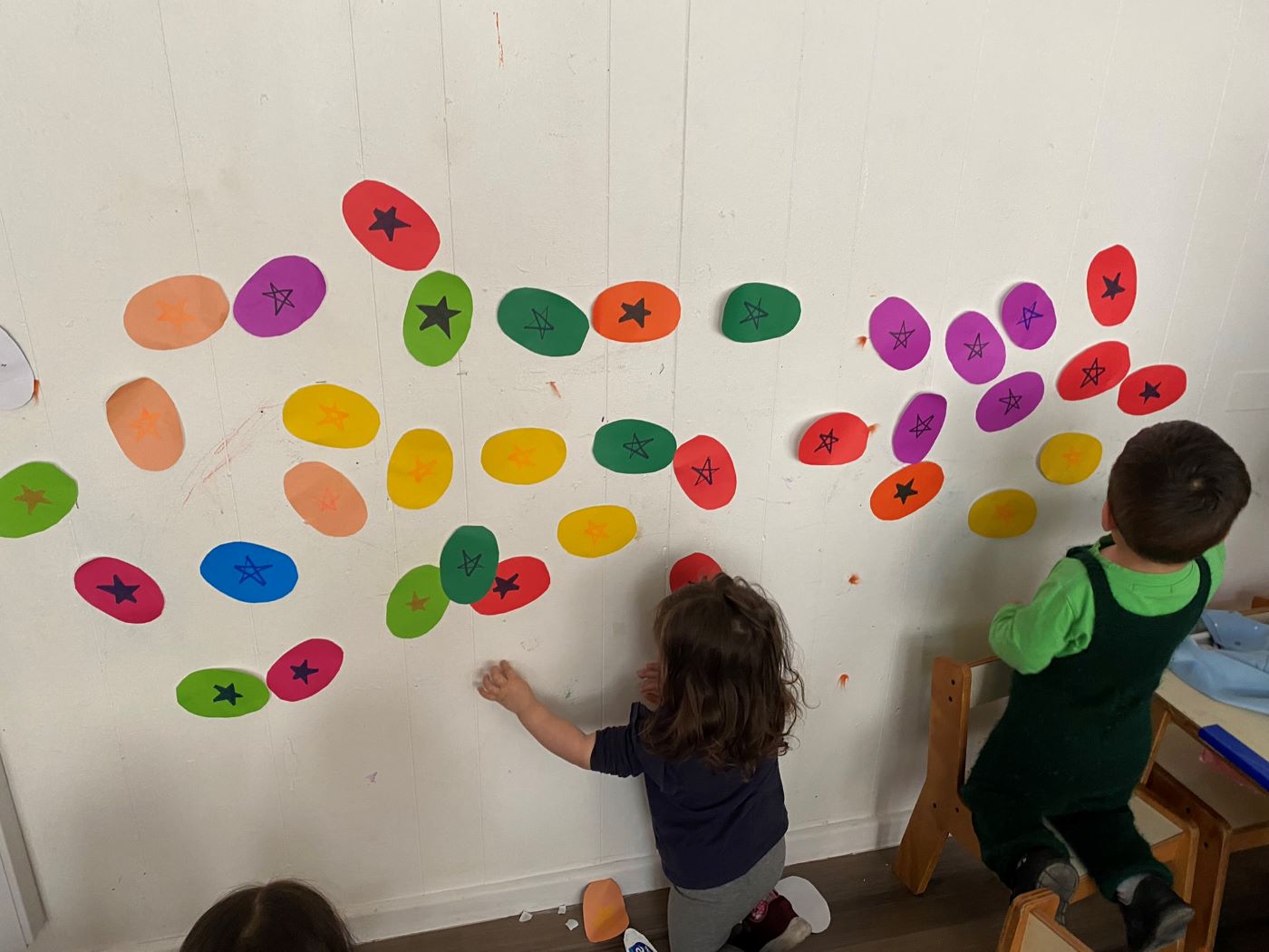 Proyecto cuentos para buscar y encontrar niños jugando con circulos de papel en el muro