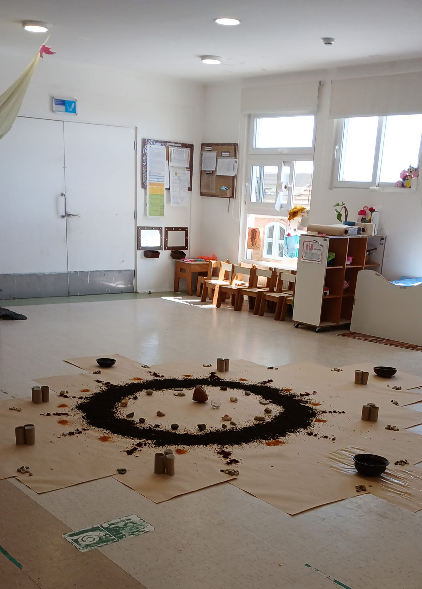 sala de clases con un circulo de diferentes materiales en el suelo