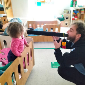 hombre haciendo sonar un instrumento frente a una niña
