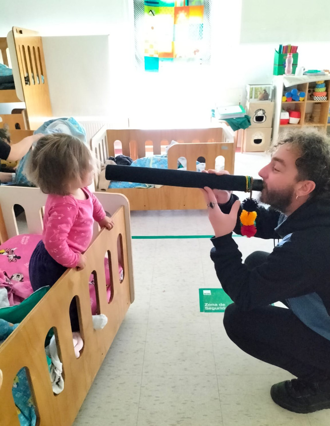 hombre haciendo sonar un instrumento frente a una niña