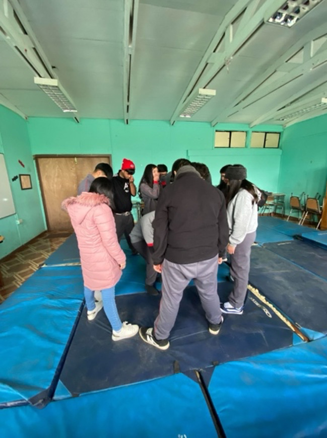 Grupo de jóvenes en círculo sobre colchonetas