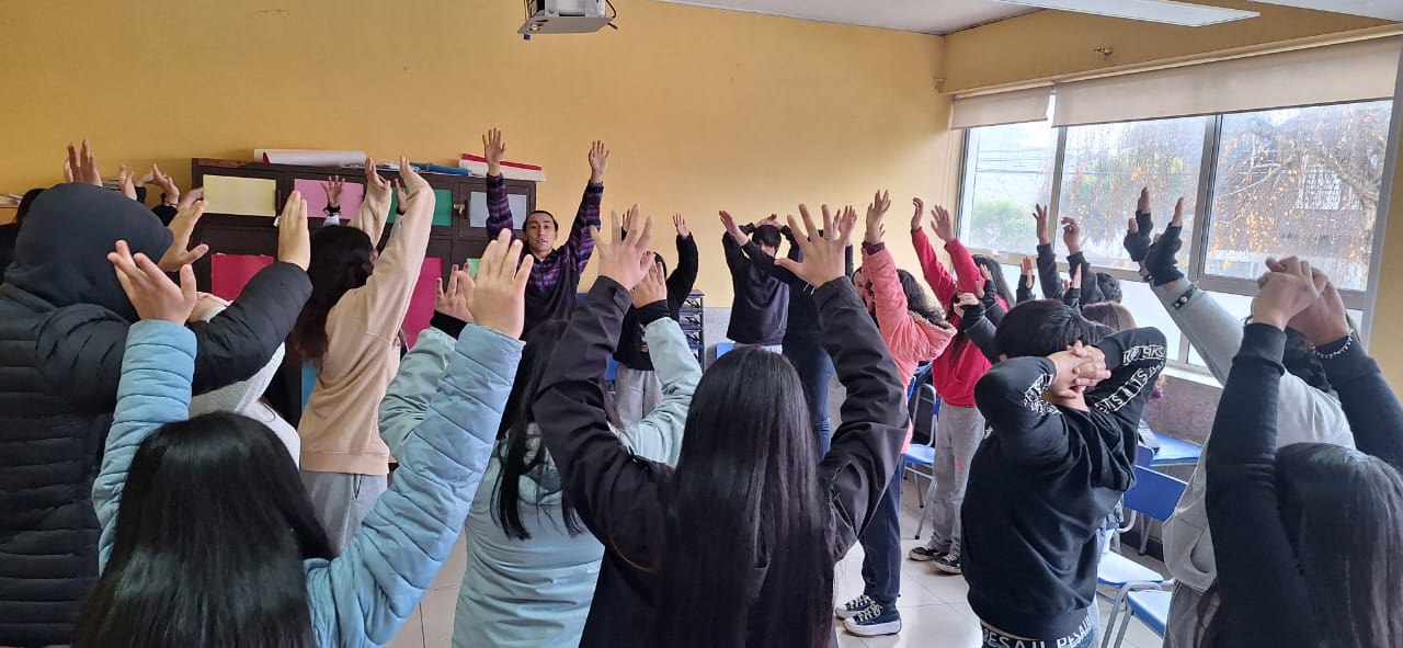 Jovenes y profesor con los brazos levantados