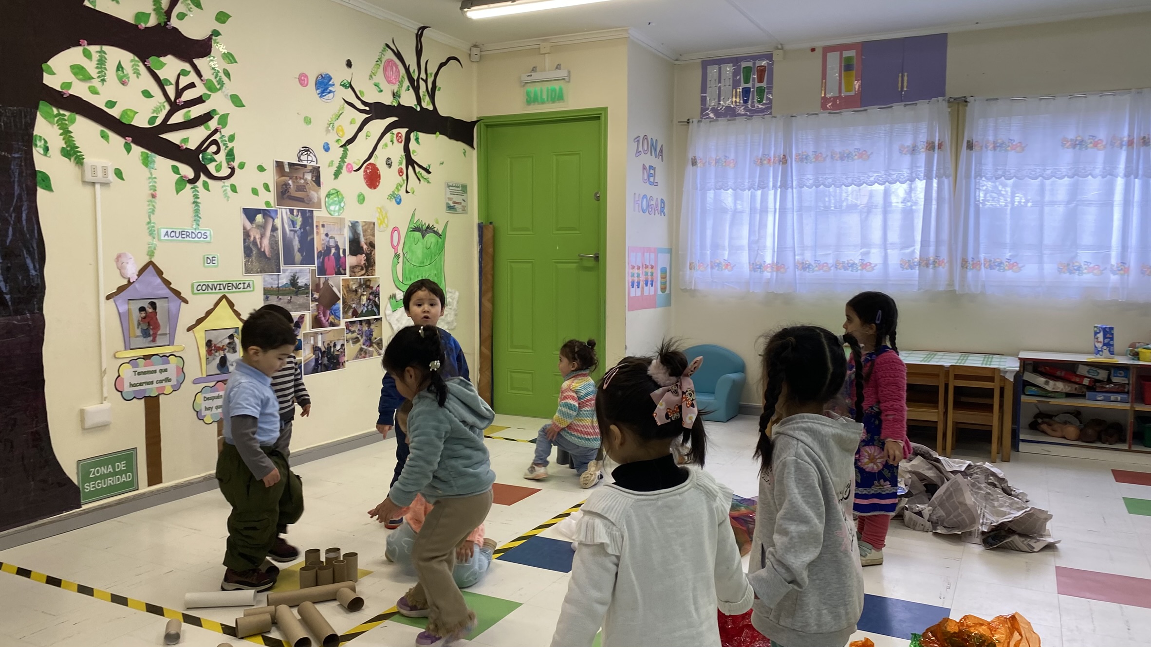 Niños jugando en sala de clases. Se encuentran haciendo actividades con conos de papel higiénico, papel celofán y papel de diario.