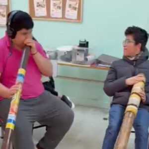 jovenes en una sala tocando instrumentos de viento