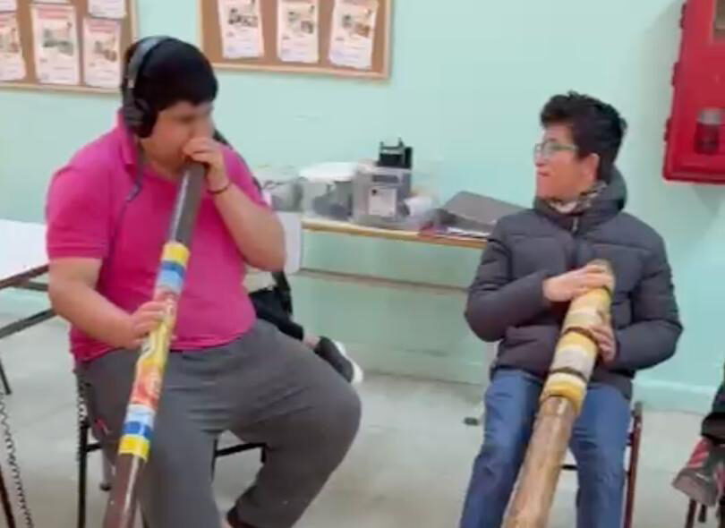 jovenes en una sala tocando instrumentos de viento