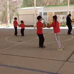 niños y niñas tomados de la mano bailando en una cancha