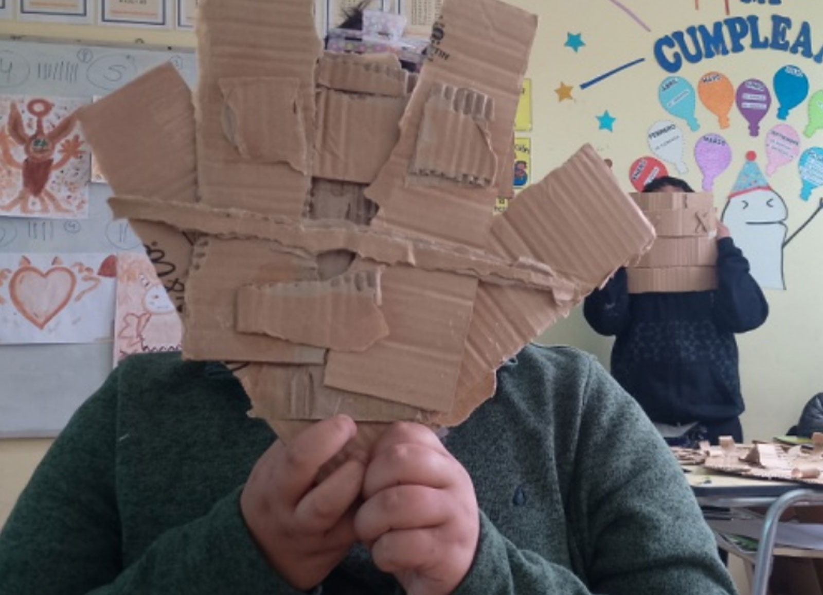 niño sosteniendo un trabajo hecho con carton
