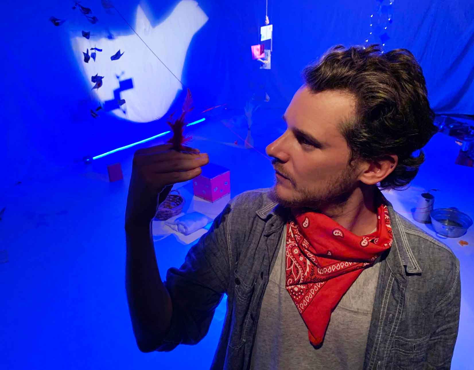artista sosteniendo una pluma en un escenario con juegos de luces