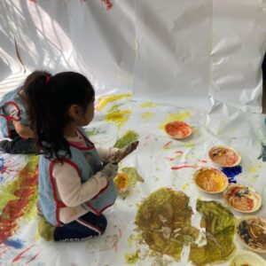 Niña jugando con pintura en el suelo