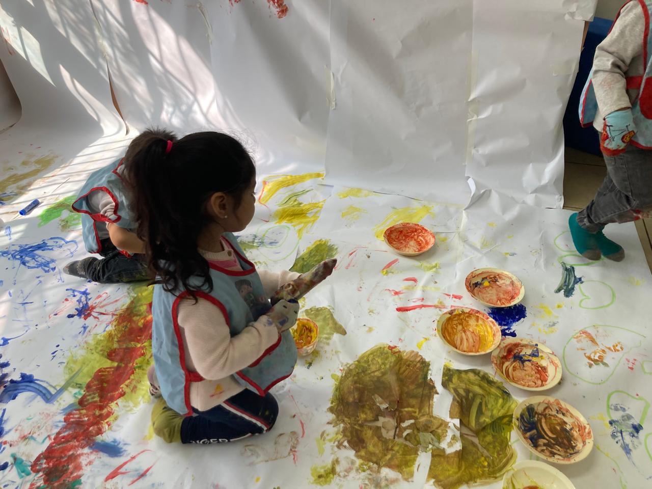 Niña jugando con pintura en el suelo