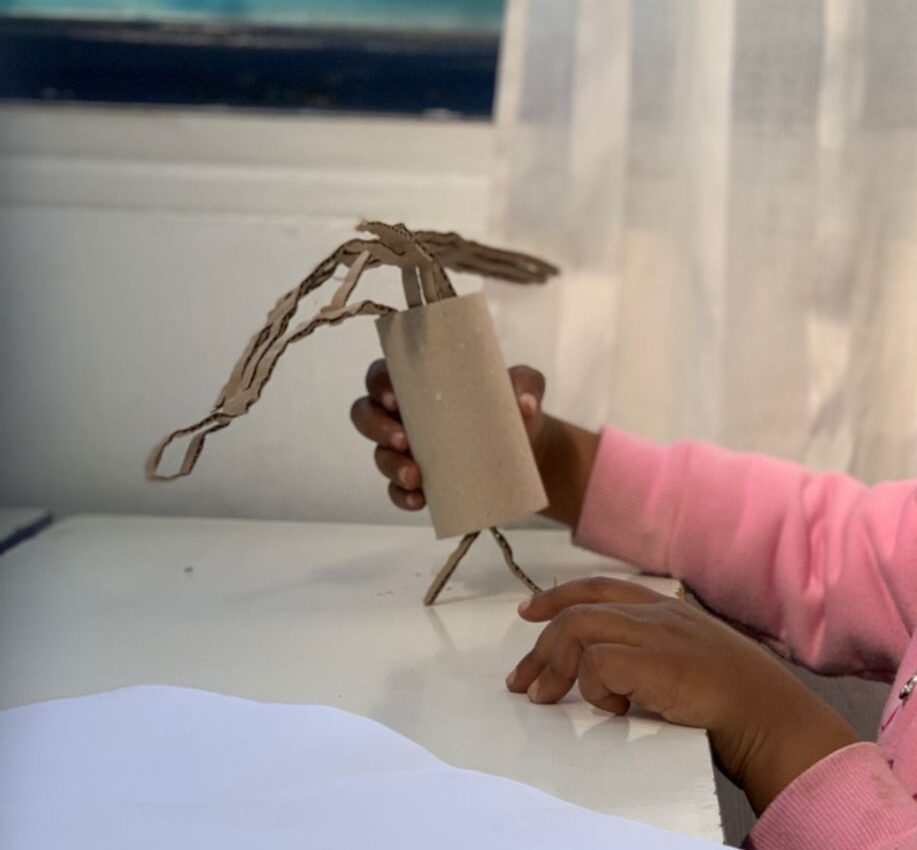 manos de niña jugando con un tubo de carton