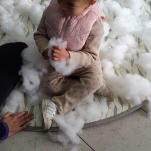 Niña pequeña jugando con algodones en el suelo
