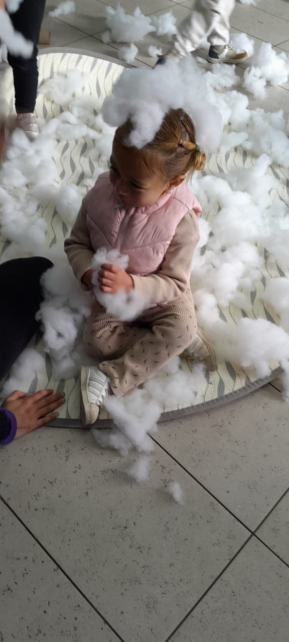 Niña pequeña jugando con algodones en el suelo
