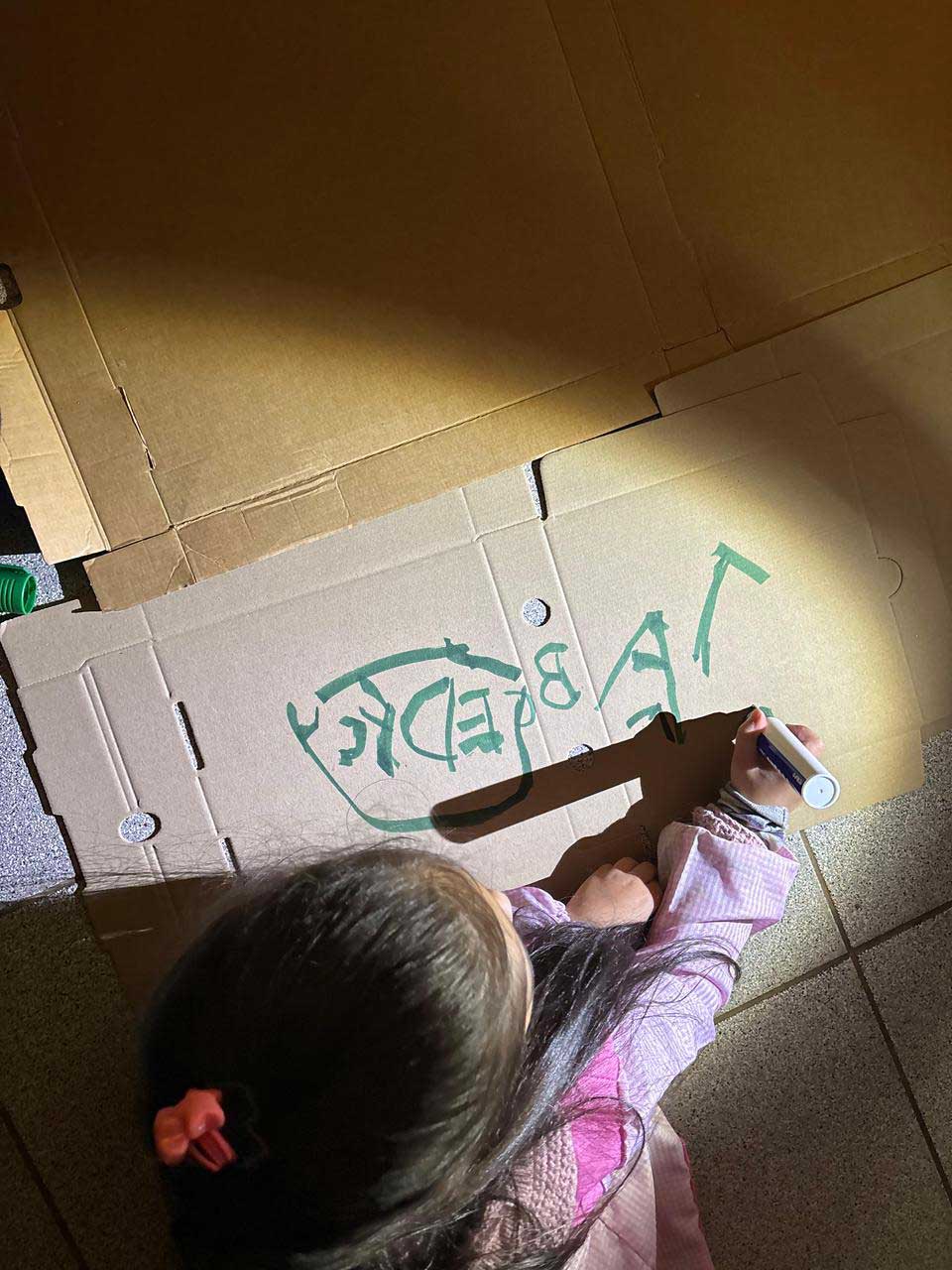 niña dibujando con un plumon sobre carton