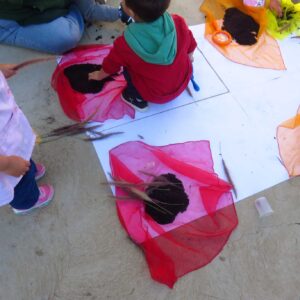 niños jugando con telas de colores y tierras