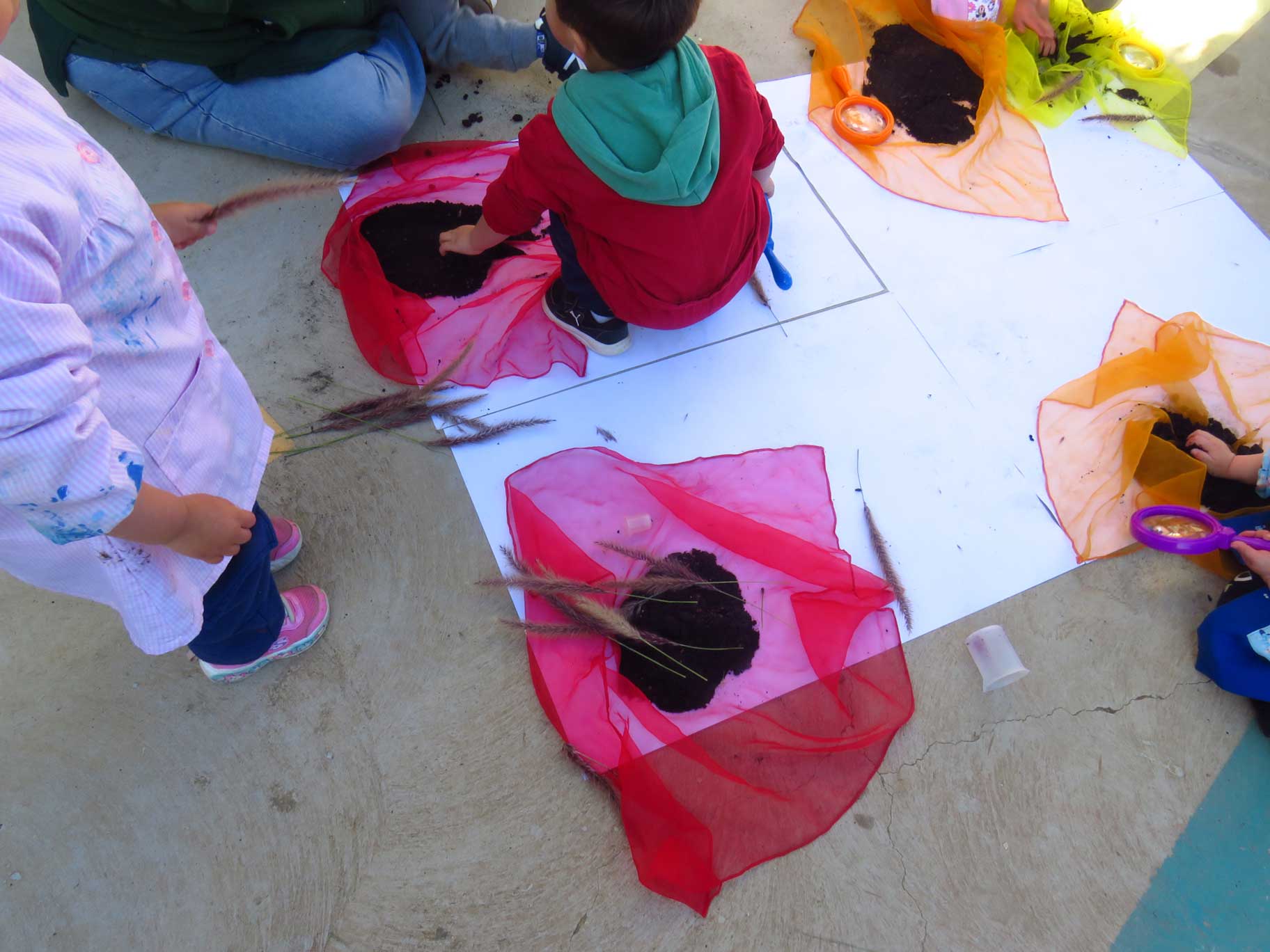 niños jugando con telas de colores y tierras