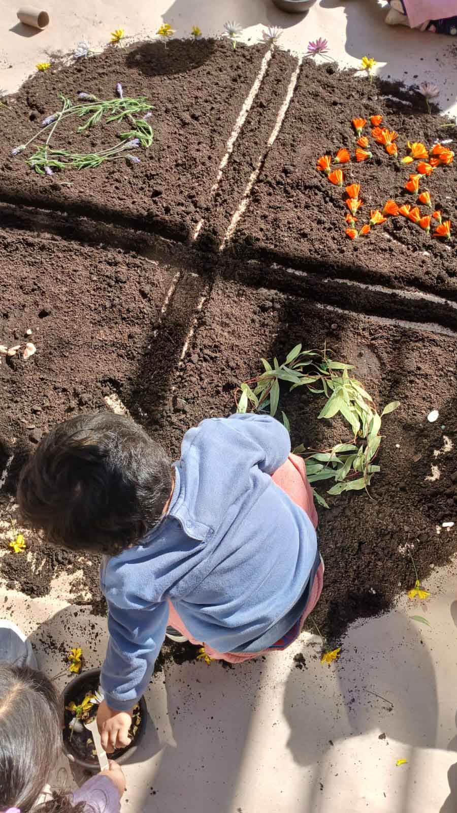 niños y niñas haciendo esquemas con flores y hojas sobre la tierra