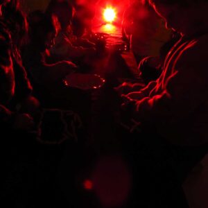 Niños y niñas en una sala oscura observando objetos con una tenue luz