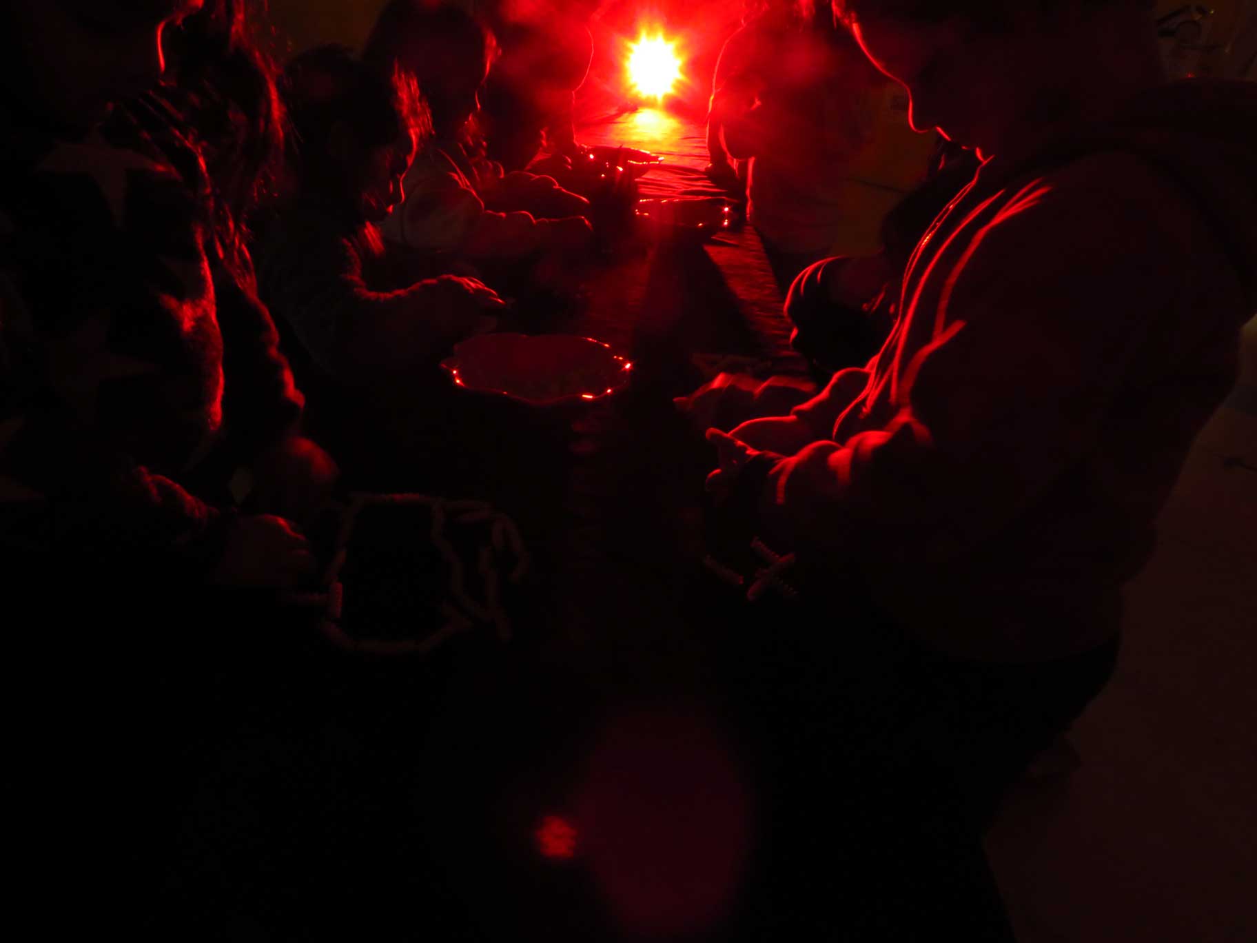Niños y niñas en una sala oscura observando objetos con una tenue luz