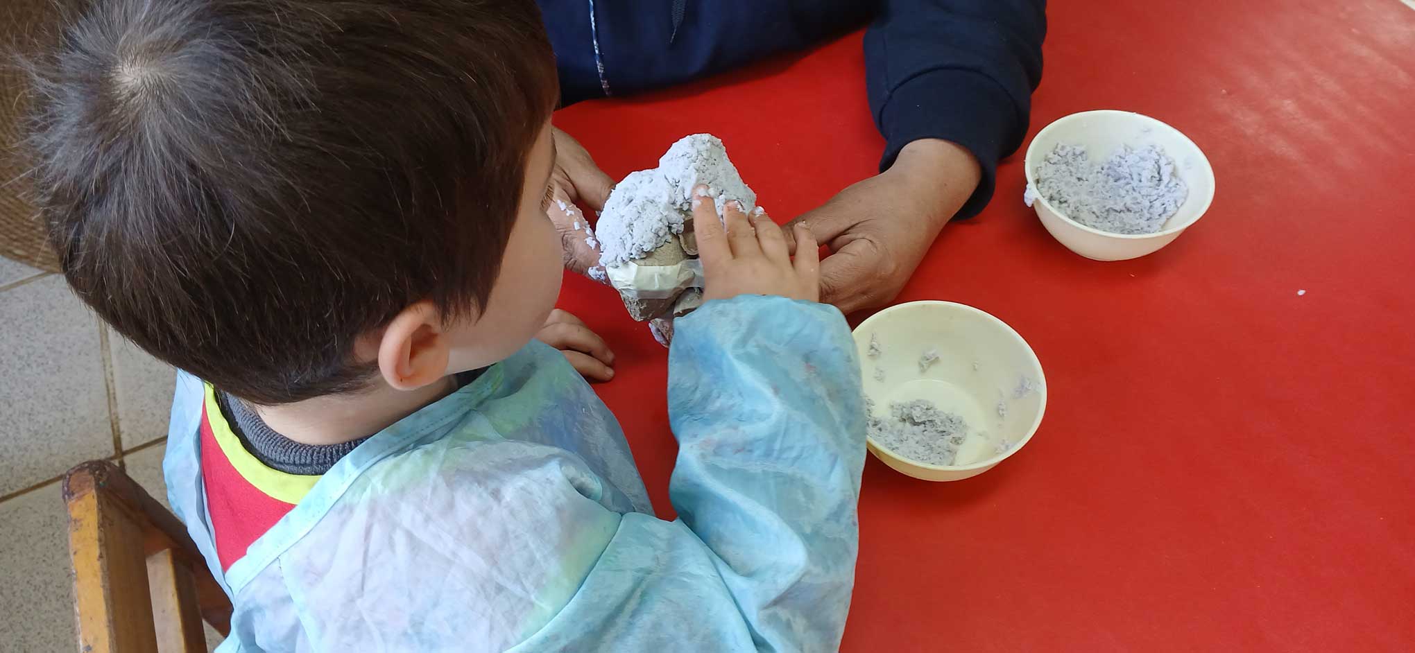 Niño trabajando con una masa de papel molido
