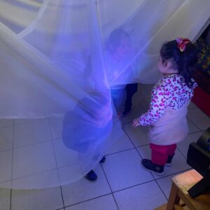 niños y niñas jugando con una tela transparente colgada