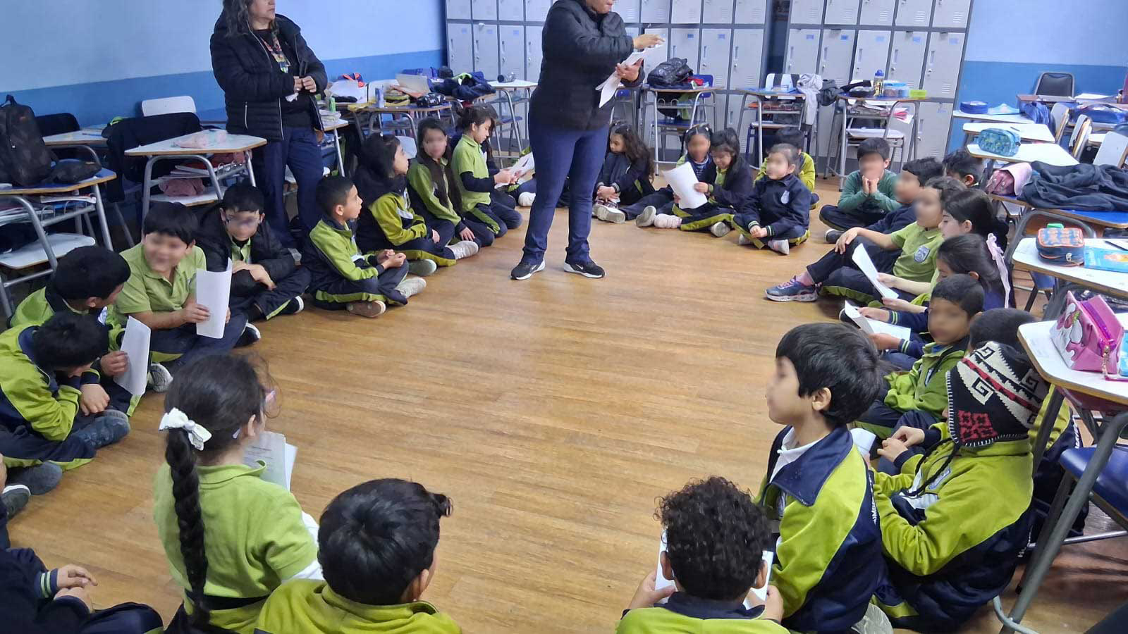 niños y niñas sentadas en un circulo dentro de la sala