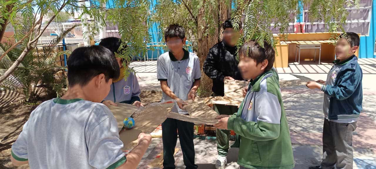 seis niños jugando con unos cartones en el patio