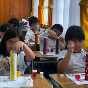 niños y niñas pintando con tempera unos tubos de carton