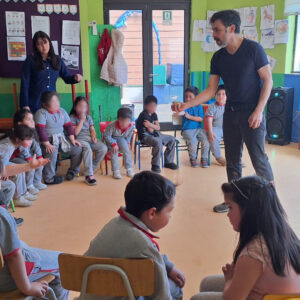 Niños sentados en sillas en medio circulo escuchando a un profesor