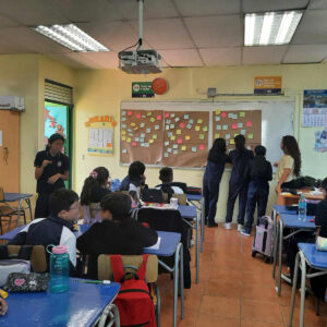 Tres niñas junto a su educadora poniendo unos papeles de colores en la pizarra